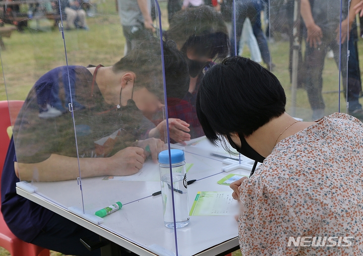 [증평=뉴시스] 강신욱 기자 = 7일 오후 충북 증평 육군 37사단에서 열린 가족 동반 입영식에 앞서 야외행사에서 가족들이 입영장정에게 전할 손편지를 쓰고 있다. 2022.06.07. ksw64@newsis.com 