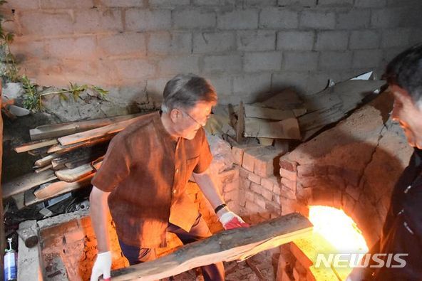 [서울=뉴시스]문재인 전 대통령이 지난 7일 경남 양산 평산마을 사저 옆 도예 작업장에서 면장갑을 끼고 가마에 장작을 보태고 있다. (사진=문 전 대통령 페이스북 캡처) 2022.06.08.