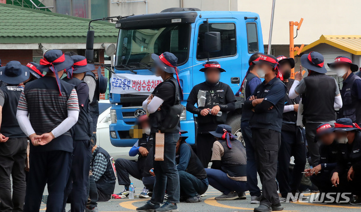 [부산=뉴시스] 하경민 기자 = 민주노총 공공운수노조 화물연대 총파업 이틀째인 8일 오후 부산 남구 감만부두 앞에서 열린 선전전에 참가한 화물연대 조합원들 뒤로 긴급 투입된 국토교통부 비상수송차량이 이동하고 있다. 2022.06.08. yulnetphoto@newsis.com