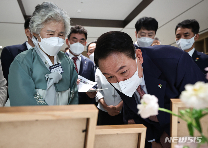 [서울=뉴시스] 윤석열 대통령이 9일 서울 용산 대통령실 청사에서 열린 '호국영웅 초청 소통식탁' 행사에 앞서 천안함 희생자 고 민평기 상사의 모친 윤청자 여사와 순직 장병 사진 등을 보며 환담하고 있다. 이날 행사에는 천안함·제2연평해전·연평도포격전 생존 장병과 유가족, 목함지뢰 사건 김정원 중사와 하재헌 예비역 중사 등 20명이 참석했다. (사진=대통령실 제공) 2022.06.09. photo1006@newsis.com