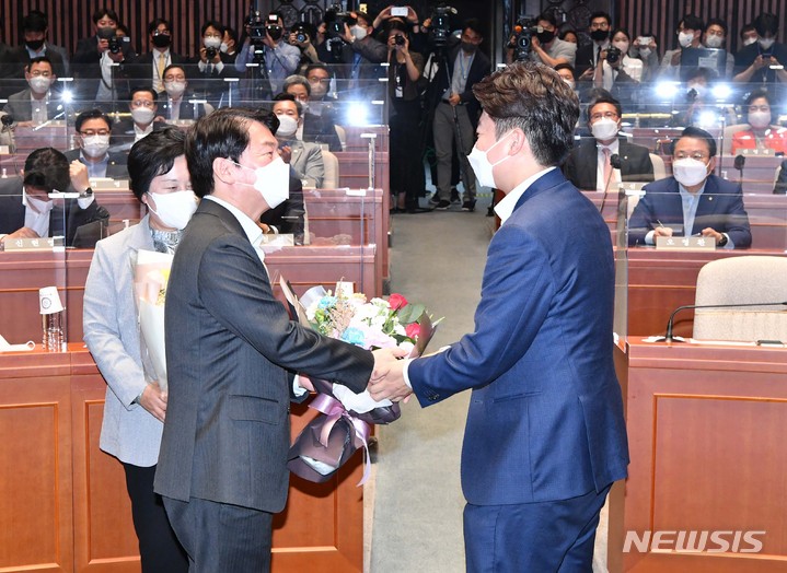 [서울=뉴시스] 김선웅 기자 = 이준석 국민의힘 대표가 지난 14일 오후 서울 여의도 국회에서 열린 의원총회에서 안철수 의원에게 꽃다발을 전달하고 있다. (공동취재사진) 2022.06.14. photo@newsis.com