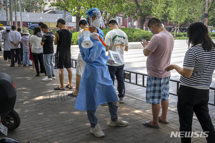 [베이징=AP/뉴시스] 지난달 15일 중국 베이징의 차오양구의 코로나19 집단 검사소에서 보호복을 입은 한 근로자가 줄 선 시민들에게 QR 코드를 보여주고 있다. 2022.06.15.