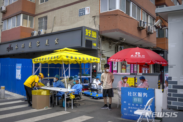 [베이징=AP/뉴시스] 15일 중국 베이징에서 보호복을 입은 근로자들이 코로나19 방제를 위해 봉쇄한 주택가 입구에 앉아 있다. 베이징의 코로나19 재확산이 계속되고 위성도시에서도 확진자가 발생하는 것으로 알려졌다. 2022.06.15.