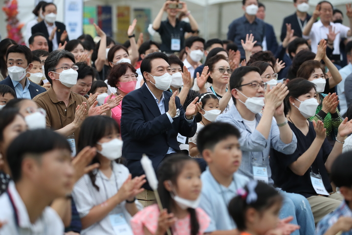 [서울=뉴시스] 전신 기자 = 윤석열 대통령이 19일 서울 용산 대통령실 청사 앞 잔디마당에서 열린 대통령실 이전 기념 어린이·주민 초대 행사에서 용산 주민들과 함께 공연을 관람하고 있다. 2022.06.19. photo1006@newsis.com