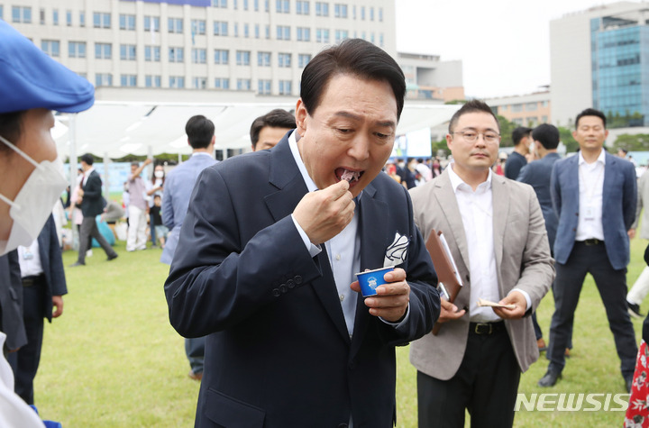 [서울=뉴시스] 전신 기자 = 윤석열 대통령이 19일 서울 용산 대통령실 청사 앞 잔디마당에서 열린 대통령실 이전 기념 어린이·주민 초대 행사에서 아이스크림을 맛보고 있다. 2022.06.19. photo1006@newsis.com