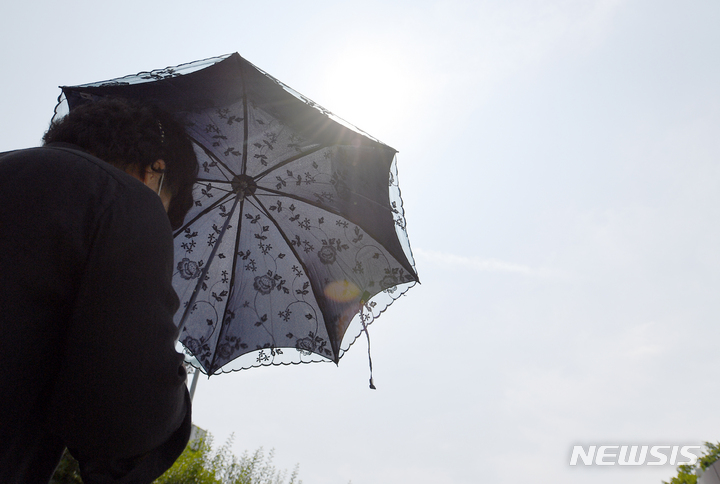 [광주=뉴시스] 류형근 기자 = 무더위가 기승을 부리고 있는 20일 오전 광주 서구 풍암호수공원에서 한 시민이 햇빛을 피하기 위해 양산을 쓰고 산책하고 있다. 2022.06.20. hgryu77@newsis.com