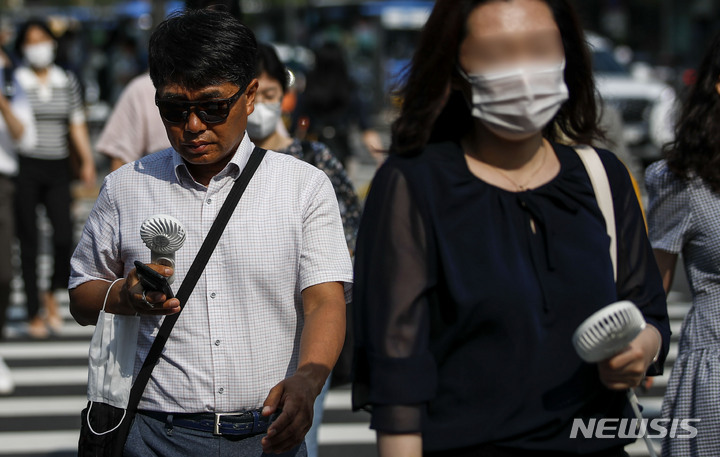 [서울=뉴시스] 정병혁 기자 = 절기상 하지이자 서울 낮 최고기온이 33도까지 오를 것으로 예보된 21일 오전 서울 종로구 광화문네거리에서 시민들이 손선풍기로 더위를 식히며 이동하고 있다. 2022.06.21. jhope@newsis.com