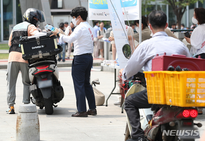 [서울=뉴시스] 김진아 기자 = 지난 2022년 6월 22일 오전 서울 종각 젊음의거리에서 열린 '2022 이동노동자를 위한 생수 나눔 캠페인'에서 배달 노동자들이 생수 등을 나눔받고 있다. 2022.06.22. bluesoda@newsis.com