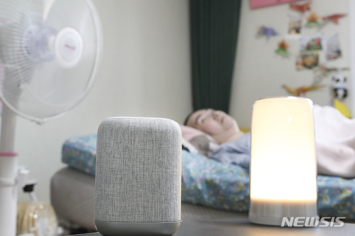 [서울=뉴시스]KT가 신체 기능에 제약이 있고 보행이 어려운 탈시설 중증장애인 가구를 대상으로 AI 케어 서비스 보급에 나섰다. 사진은 중증장애인 A씨가 서울 홍제동 자택에서 AI 케어서비스를 통해 간단한 음성명령만으로 댁내 가전을 제어하고 있는 모습. (사진=KT 제공)