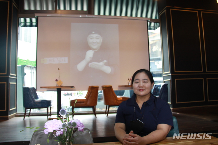 [포항=뉴시스] 이바름 기자 = 경북 포항에서 농아인들과 함께 '수화식당(signing restaurant)'을 운영하는 김소향(47·여) 대표. 뒤로 직원들이 수화를 설명하는 영상이 나오고 있다. 2022.06.24. right@newsis.com
