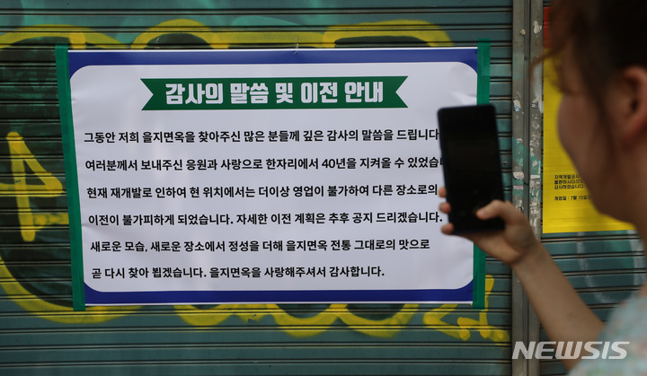 [서울=뉴시스] 조수정 기자 = 37년 전통의 서울 평양냉면 맛집인 을지면옥 영업 마지막 날인 25일 오후 서울 중구 을지면옥에서 한 소비자가 감사 인사와 이전 안내문을 보고 있다. 세운재정비촉진지구 3-2구역 재개발 시행사가 을지면옥을 상대로 낸 '부동산명도단행가처분'에서 법원은 1심을 뒤집고 시행사의 손을 들어줬다. 을지면옥은 새로운 장소를 찾아 이전할 계획이다. 2022.06.25. chocrystal@newsis.com