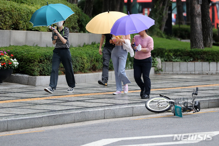[서울=뉴시스] 백동현 기자 = 비가 내리는 28일 오후 서울 중구 세종대로 인근에서 우산을 쓴 시민들 옆으로 자전거가 바람에 쓰러져 있다. 2022.06.28. livertrent@newsis.com