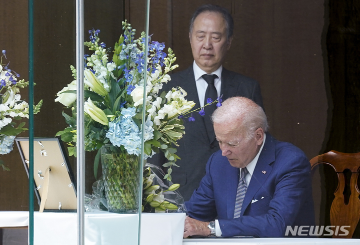 [워싱턴=AP/뉴시스] 도미타 고지(冨田浩司) 주미국 일본대사는 6일(현지시간) 한미일 정상회의 정례화 실현을 위해서는 "첫째로 한일 관계 개선을 계속하는 게 필요하다"고 강조했다. 사진은 가두 연설 중 총격으로 사망한 아베 신조 전 일본 총리를 위해 조 바이든 미국 대통령이 워싱턴에 있는 주미 일본대사관저에서 조문록에 2022년 7월 8일 서명하고 있는 모습. 이를 도미타 대사가 지켜보고 있다. 2023.09.07.