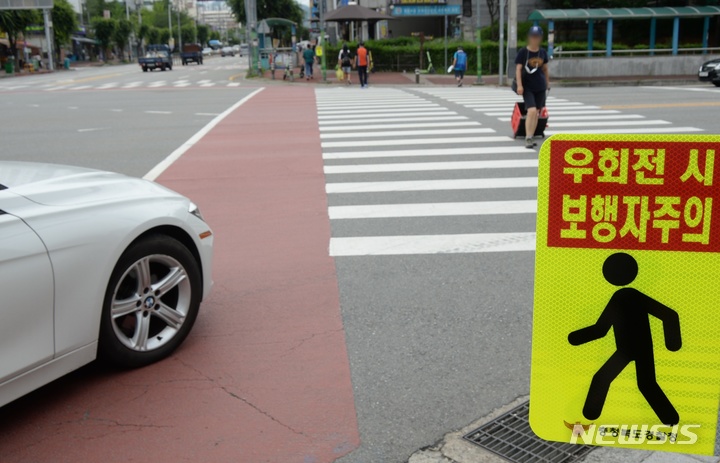 [청주=뉴시스] 조성현 기자 = 횡단보도 앞 일시정지 등 보행자 보호 의무를 강화한 도로교통법 개정안 시행 첫날인 12일 충북 청주시 상당구 용암동 인근 도로에서 경찰들이 계도 활동에 나서고 있다. 개정된 도로교통법에 따르면 모든 운전자는 횡단보도에 보행자가 통행하고 있는 경우뿐만 아니라 '통행하려고 하는 때'에도 일시 정지해야 한다. 어린이 보호구역 내의 신호 없는 횡단보도에서는 보행자의 통행 여부와 관계없이 멈춰야 한다. 이를 위반하는 경우 승용차 기준 범칙금 6만원과 10점의 벌점이 부과된다. 2022.07.12. jsh0128@newsis.com 