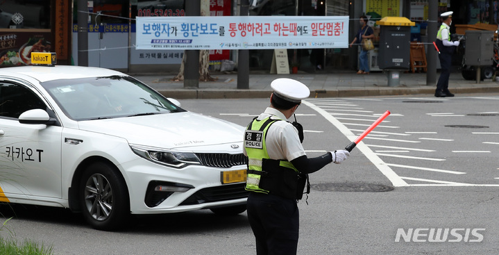 [서울=뉴시스] 이영환 기자 = 횡단보도 앞 일시정지 의무를 확대하는 등 보행자 보호의무가 강화된 도로교통법 개정안이 시행된 12일 오전 서울 종로구 이화사거리에서 혜화경찰서 경찰관들이 계도 활동을 하고 있다. 경찰청은 이날부터 1개월간 계도·홍보 위주의 안전 활동 기간을 지정해 전국적으로 실시하고, 법 개정 사항이 교통 문화로 정착될 때까지 홍보영상, 현수막, 카드뉴스 등을 통해 적극 홍보에 나설 계획이라고 밝혔다. 2022.07.12. 20hwan@newsis.com