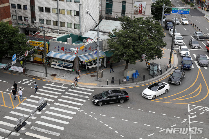 [서울=뉴시스] 백동현 기자 = 횡단보도 앞 일시정지 의무를 확대하는 등 보행자 보호의무가 강화된 도로교통법 시행 첫날인 12일 오후 서울 시내 한 횡단보도에서 우회전하는 차량이 보행자의 횡단을 기다리고 있다. 2022.07.12. livertrent@newsis.com