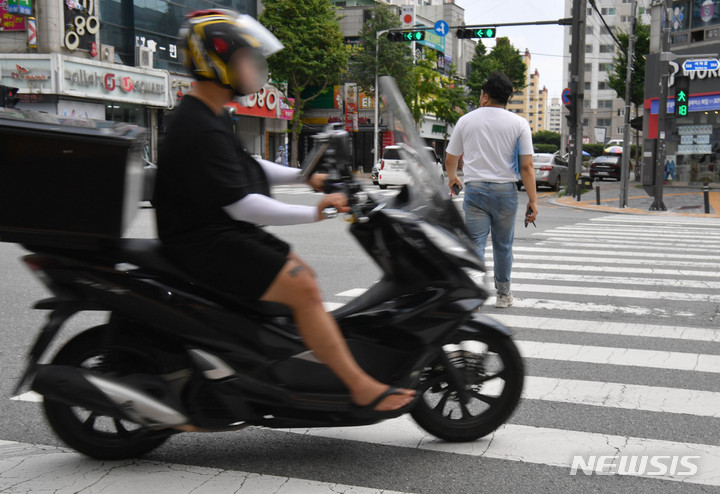 [광주=뉴시스] 변재훈 기자 = 경찰청은 보행자 교통안전을 위협하는 이륜차 등의 보도 통행 행위를 근절하기 위해 '보도 통행 단속장비'를 개발해 16일부터 전국 5곳에서 시범 운영한다고 밝혔다. 사진은 2022년 7월 광주 북구 문흥동 한 교차로에서 이륜차가 보행자가 통행 중인 횡단보도를 지나가고 있는 모습. 2022.07.12. wisdom21@newsis.com
