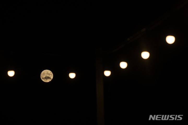 [그리스=AP/뉴시스] 13일(현지시간) 그리스 펠로폰네소스 북부 에지오 마을 근처 가로등 사이로 슈퍼문이 떠 있다. 2022.07.14.