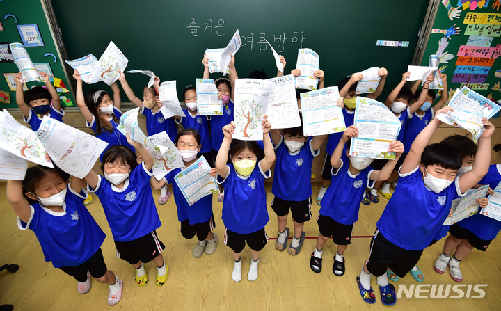 [대구=뉴시스] 이무열 기자 = 15일 오전 대구 중구 경북대학교 사범대학 부설초등학교 1학년 학생들이 방학식에서 선생님에게 전달받은 방학 활동이 적힌 통신문을 들어 보이고 있다. 2022.07.15. lmy@newsis.com