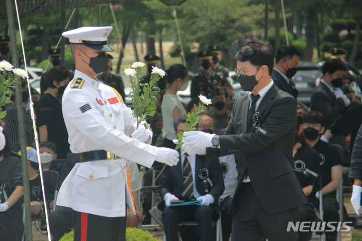 [포항=뉴시스] 이바름 기자 = 17일 오전 경북 포항특정경비지역사령부 내 마린온 순직자 위령탑에서 마린온 순직자 4주기 추모행사가 열린 가운데 마린온 순직자 유가족이 해병대원으로부터 국화를 건네받고 있다. 2022.07.17. right@newsis.com