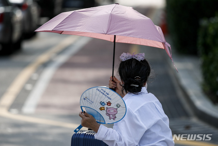 [서울=뉴시스] 정병혁 기자 = 지난 19일 오전 서울 종로구 광화문네거리에서 한 시민이 양산과 부채로 더위를 피하고 있다. 2022.07.19. jhope@newsis.com