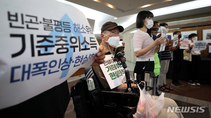 [서울=뉴시스] 지난 2022년 7월 19일 기초생활보장법바로세우기공동행동과 장애인과 가난한 사람들의 3대 적폐폐지 공동행동이 2022 제3차 생계.자활급여 소위원회가 열리는 서울 중구 프레스센터에서 '기준중위소득 인상' 등을 촉구하는 피켓팅을 하는 모습. (사진=뉴시스 DB) 2022.07.19. photo@newsis.com