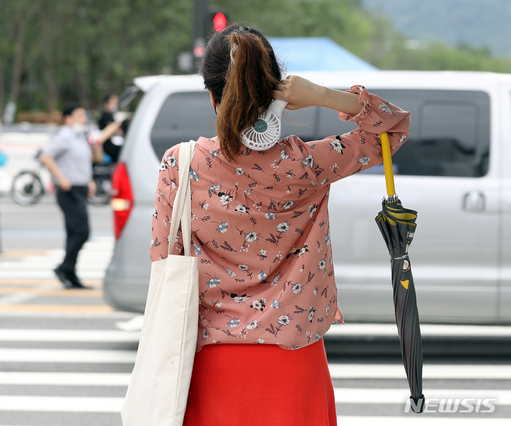 [서울=뉴시스] 김금보 기자 = 비가 그치고 습도 높은 날씨를 보인 21일 오후 서울 종로구 세종대로사거리에서 한 시민이 우산을 접고 손 선풍기로 땀을 식히고 있다. 2022.07.21. kgb@newsis.com