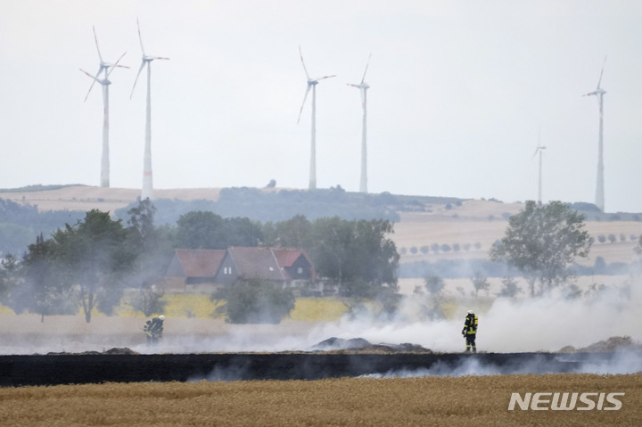 [베르니게로데=AP/뉴시스] 21일(현지시간) 독일 베르니게로데 인근에서 화재가 발생한 후 한 소방관들이 불에 탄 옥수수밭을 살피고 있다. 오랜 가뭄과 이어지는 폭염으로 독일 전역에서 산불의 위험이 커지고 있다. 2022.07.22.