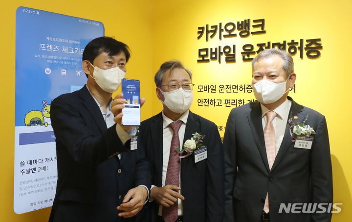 [서울=뉴시스] 김금보 기자 = 이상민 행정안전부 장관(오른쪽), 고진 디지털플랫폼정부위원회 출범준비단 단장(왼쪽), 윤호영 카카오뱅크 대표가 28일 오전 서울 강서운전면허시험장에서 열린 모바일운전면허증 전국발급 개통식에서 모바일 운전면허증 이용한 금융 서비스 이용을 시연하고 있다. 2022.07.28. kgb@newsis.com