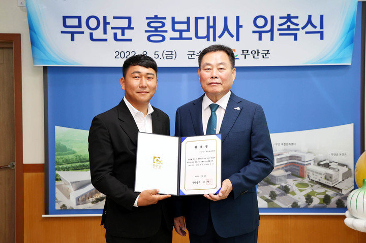 [무안=뉴시스] 박상수 기자 = 김산(오른쪽) 전남 무안군수가 5일 군수실에서 무안군 홍보대사로 위촉된 청년농부 가수 농수로(박주안 씨)와 기념촬영을 하고 있다. (사진=무안군 제공) 2022.08.05. photo@newsis.com *재판매 및 DB 금지