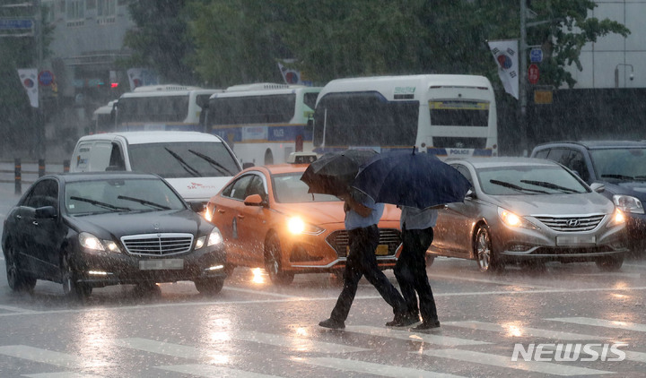 [서울=뉴시스] 고범준 기자 = 서울 등 중부를 중심으로 폭우가 쏟아지는 8일 오후 서울 여의도 국회 정문 앞에서 시민들이 우산을 쓰고 지나가고 있다. 2022.08.08. bjko@newsis.com