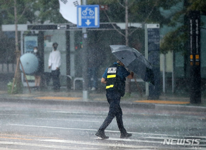 [서울=뉴시스] 고범준 기자 = 서울 등 중부를 중심으로 폭우가 쏟아지는 8일 오후 서울 여의도 국회 정문 앞에서 한 경찰이 우산을 쓰고 지나가고 있다. 2022.08.08. bjko@newsis.com