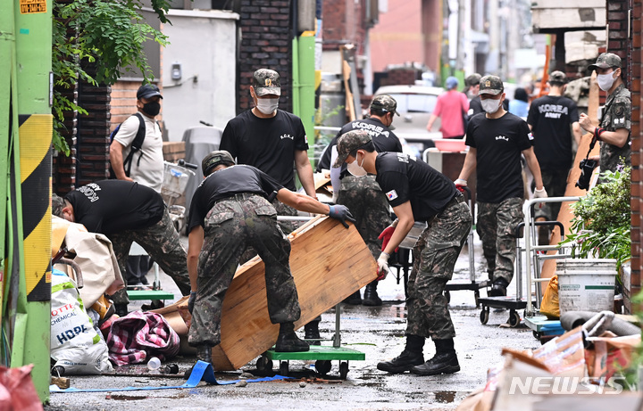 [군포=뉴시스] 김종택기자 = 수도권 등 중부지방에 내린 폭우로 피해가 속출하고 있는 11일 오후 경기도 군포시 산본동 저지대 주택가에서 육군 제51보병사단 예비군지휘관과 상근 예비역들이 복구작업 지원에 나서 침수가구 집기류 등 폐기물을 처리하고 있다. 2022.08.11. jtk@newsis.com