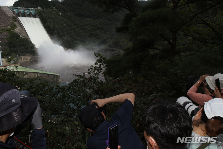 [춘천=뉴시스] 김경목 기자 = 11일 오후 시민들이 강원 춘천시 소양강댐이 보이는 야산 중턱에서 2년 만에 수문을 열고 한강으로 방류하는 소양강댐의 광경을 지켜보고 있다. 한국수자원공사 소양강댐지사는 한강홍수통제소의 방류 승인을 받고 초당 435.73ｔ의 물을 방류했다. 2022.08.11. photo31@newsis.com