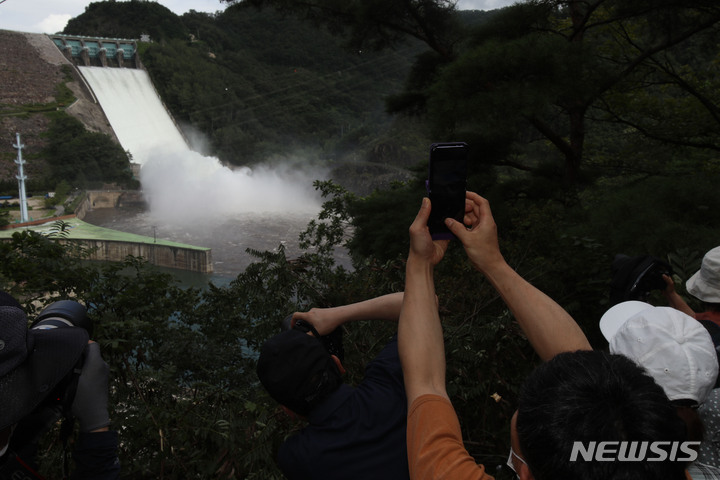 [춘천=뉴시스] 김경목 기자 = 11일 오후 시민들이 강원 춘천시 소양강댐이 보이는 야산 중턱에서 2년 만에 수문을 열고 한강으로 방류하는 소양강댐의 광경을 지켜보고 있다. 한국수자원공사 소양강댐지사는 한강홍수통제소의 방류 승인을 받고 초당 435.73ｔ의 물을 방류했다. 2022.08.11. photo31@newsis.com