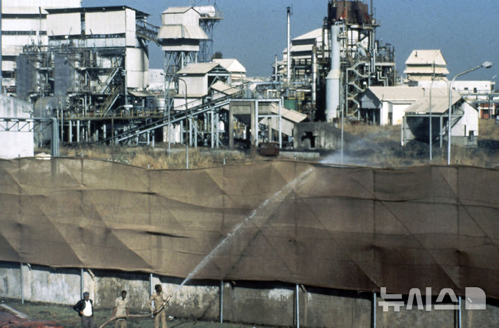 [보팔(인도)=AP/뉴시스]인도 보팔의 유니언 카바이드 공장에서 1984년 12월3일 소방관들이 위험한 연기가 퍼지는 것을 막기 위해 공장 경계에 설치된 캔버스 스크린을 적시기 위해 호스로 물을 뿌리고 있다. 인도가 1884년 12월 수천명의 목숨을 앗아간 보팔 가스누출 사고를 일으킨 보팔 유니언 카바이드 화학공장의 유독성 폐기물 수백t을 사고 발생 40년 만에 제거했다고 BBC가 2일 보도했다. 2025.01.02.