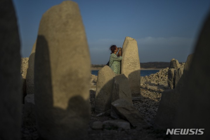 [마누페르난데즈=AP/뉴시스] 13일(현지시간) 스페인 서부지역 엘 고르도에 발데카냐스 저수지에서 극심한 가뭄으로 인해 나타난 거석 기념물 '과달페랄 고인돌' 옆에 아말리 가르시아(54)가 서 있다. 세 번의 기록적인 폭염과 적은 강수량으로 인해 스페인 저수지가 일주일째 말라있다. 60년 만에 2번째로 찾아온 가뭄은 건조한 겨울에 찾아왔던 첫 번째 가뭄보다 일찍 시작된 것으로 알려졌다. 2022.08.24.