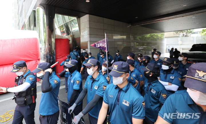 [서울=뉴시스] 김금보 기자 = 전국민주노동조합총연맹 공공운수노조 화물연대 조합원들이 16일 오전 서울 강남구 하이트진로 본사를 점거하고 옥상 투신위협 농성을 하고 있다. 이날 오전 경찰이 하이트진로 본사 출입구를 통제하고 있다. 2022.08.16. kgb@newsis.com