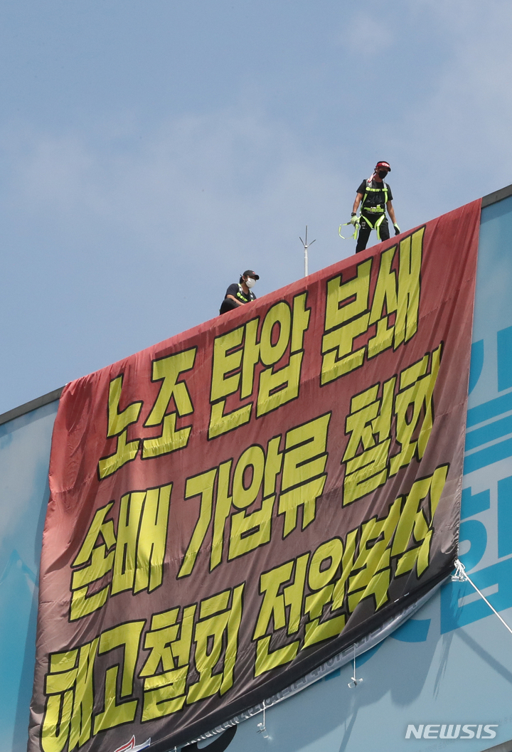 [서울=뉴시스] 김금보 기자 = 전국민주노동조합총연맹 공공운수노조 화물연대 조합원들이 16일 오전 서울 강남구 하이트진로 본사 옥상에 대형 현수막을 설치하고 점거농성을 하고 있다. 2022.08.16. kgb@newsis.com