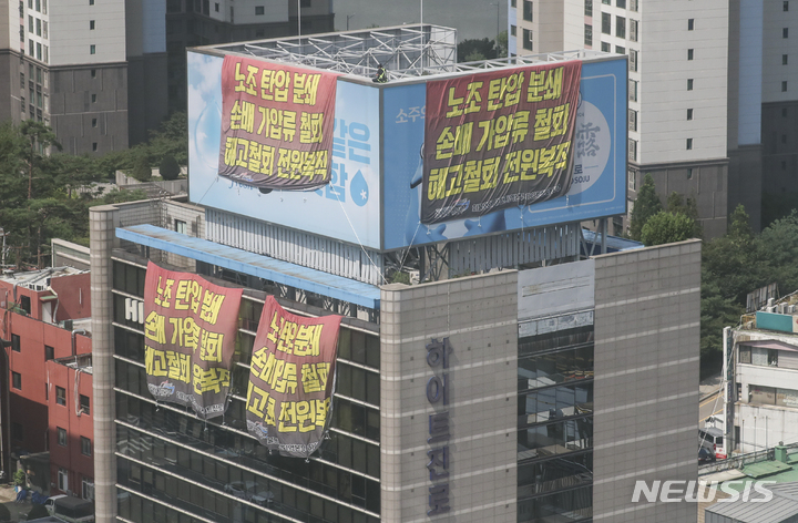 [서울=뉴시스] 김근수 기자 = 전국민주노동조합총연맹 공공운수노조 화물연대 조합원들이 17일 오후 서울 강남구 하이트진로 본사 옥상에 대형 현수막을 설치하고 이틀째 점거농성을 하고있다. 2022.08.17. ks@newsis.com