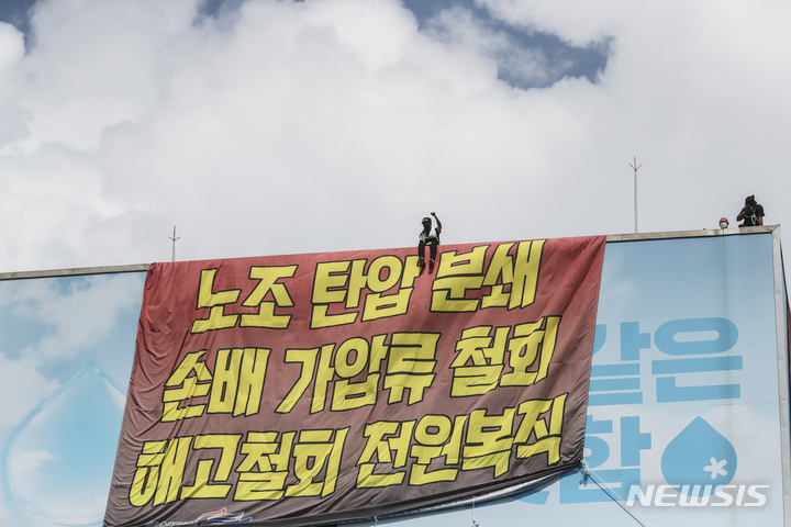 [서울=뉴시스] 김근수 기자 = 전국민주노동조합총연맹 공공운수노조 화물연대 조합원들이 17일 오후 서울 강남구 하이트진로 본사 옥상에 대형 현수막을 설치하고 이틀째 점거농성을 하고있다. 2022.08.17. ks@newsis.com