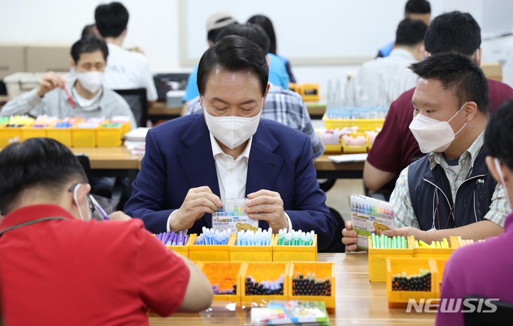 [서울=뉴시스] 홍효식 기자 = 윤석열 대통령이 18일 서울 강남구 충현복지관을 방문해 발달장애인 훈련생 및 근로인과 보호작업장에서 색연필 포장 작업을 체험하고 있다. (대통령실통신사진기자단) 2022.08.18. yesphoto@newsis.com