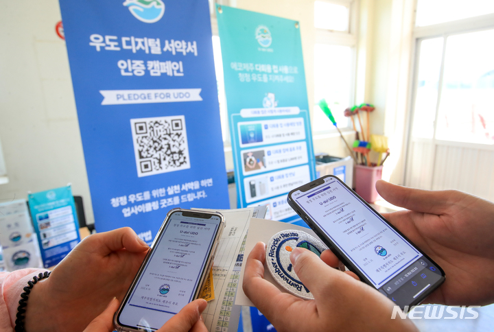 [서귀포=뉴시스] 우장호 기자 = 제주 서귀포시 성산포항에서 우도로 향하는 도항선 탑승 전 관광객들이 '청정 우도를 위한 실천' 디지털 서약에 참여하고 있다. 2022.08.19. woo1223@newsis.com