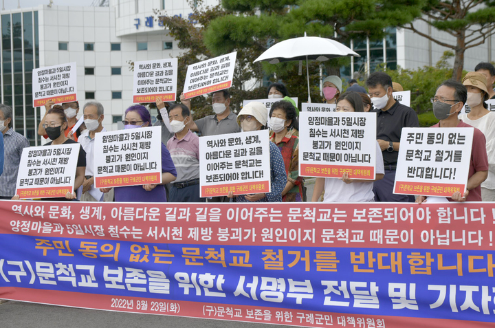 [광주=뉴시스]김혜인 기자 = 구 문척교 보존을 위한 구례군민 대책위원회가 23일 오전 전남 구례군청 앞에서 기자회견을 열어 문척교 철거 철회를 촉구하고 있다. 2022.08.23.(사진= 문척교 보존을 위한 구례군민 대책위원회 제공) photo@newsis.com