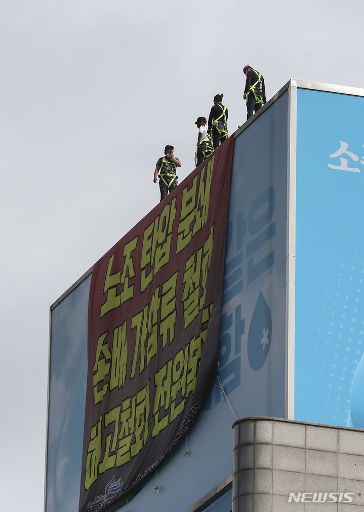 [서울=뉴시스] 김근수 기자 = 전국민주노동조합총연맹 공공운수노조 화물연대 조합원들이 하이트진로 본사 로비 점거를 해제한 24일 오전 서울 강남구 하이트진로 본사 옥상에서 조합원이 내려다보고 있다. 민주노총 공공운수노조 화물연대는 고공농성은 유지하되 하이트진로와 대화를 진행하기 위해 본사 로비 점거를 해제한다고 밝혔다. 2022.08.24. ks@newsis.com