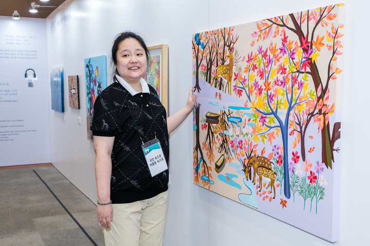 [서울=뉴시스] 청와대 춘추관에서 열리고 있는 장애예술인 특별전 ‘국민 속으로 어울림 속으로’ 전시장에서 참여작가인 이다래 씨가 본인의 작품 ‘가을 숲 속의 사슴들’ 앞에 서 있다. (사진=문화체육관광부 제공) 2022.09.04. photo@newsis.com *재판매 및 DB 금지