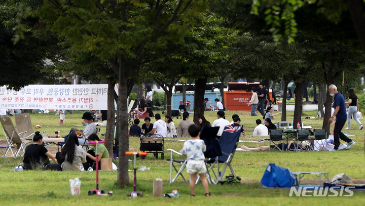 [서울=뉴시스] 서울 영등포구 여의도한강공원에서 가족단위 나들이객이 나무그늘 안에 모여 휴식을 취하고 있다. (사진=뉴시스 DB).