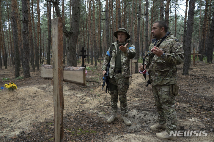 [이지움=AP/뉴시스] 우크라이나 군인들이 15일(현지시간) 우크라이나 하르키우주 이지움에서 발견된 집단매장 묘지를 살펴보고 있다. 2022.09.16.