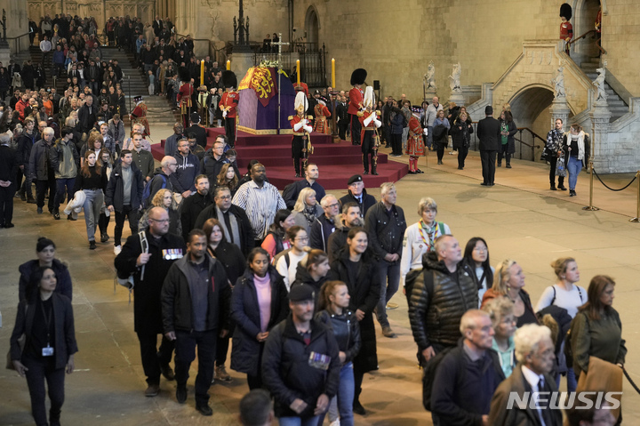 [AP/뉴시스] 18일 오후 웨스트민스터 홀 중앙에 안치된 서거여왕의 관 양쪽으로 조문객의 '물결'이 쉬지 않고 흘러가고 있다. 사람들은 관대 앞에서 아주 짤막한 시간 동안 몸을 돌려 목례하고 금방 걸음을 재촉해야 한다. 여기까지 오는 데 10시간 이상이 걸렸다.&nbsp; 
