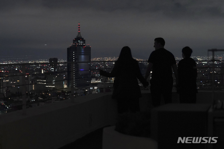 [멕시코시티=AP/뉴시스] 22일(현지시간) 멕시코 미초아칸주에서 사흘 만에 또다시 지진이 발생한 가운데 멕시코시티의 한 가족이 아파트 옥상에 올라 시내를 바라보고 있다. 이날 미초아칸주에서 규모 6.8의 강진이 발생해 최소 2명이 숨지고 진원지 인근에서 산사태가 일어나는 등 피해가 발생했다. 2022.09.23